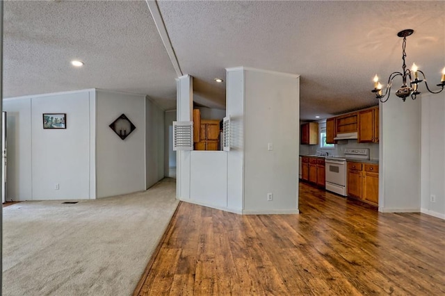 kitchen with white range with electric cooktop, open floor plan, a textured ceiling, brown cabinetry, and a chandelier