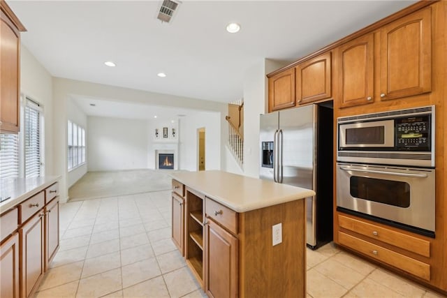230 Collins View Ct, Lawrenceville, GA 30043 - kitchen featuring appliances with stainless steel finishes, a center island, a lit fireplace, light tile patterned floors, and recessed lighting