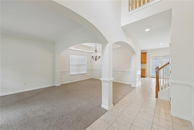230 Collins View Ct, Lawrenceville, GA 30043 - foyer entrance with a chandelier, arched walkways, light carpet, a decorative wall, and wainscoting
