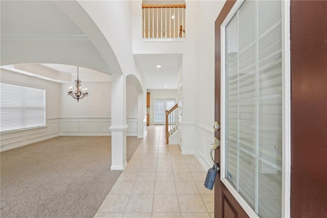 230 Collins View Ct, Lawrenceville, GA 30043 - entrance foyer with a decorative wall, a chandelier, light tile patterned floors, arched walkways, and wainscoting