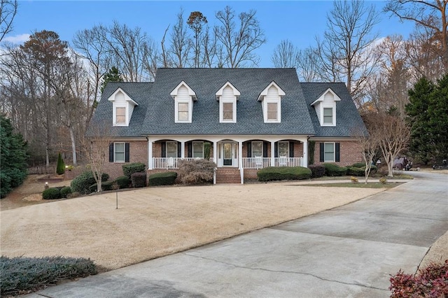 cape cod house with brick siding, covered porch, and driveway