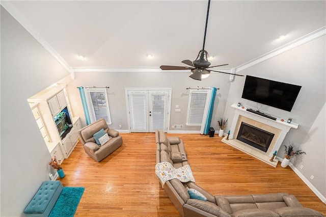 living area featuring vaulted ceiling, ornamental molding, a premium fireplace, wood finished floors, and a ceiling fan