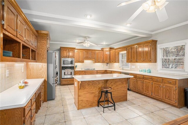 kitchen with decorative backsplash, a kitchen island, crown molding, and appliances with stainless steel finishes