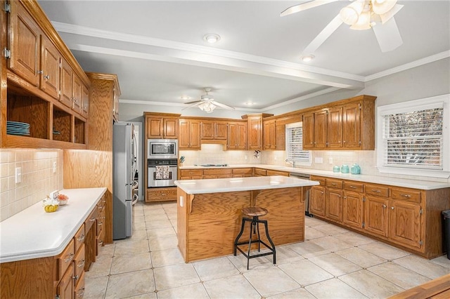 kitchen featuring brown cabinetry, a ceiling fan, stainless steel appliances, a kitchen breakfast bar, and a center island