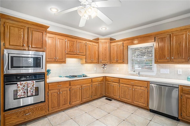 kitchen featuring brown cabinets, appliances with stainless steel finishes, light countertops, and a sink