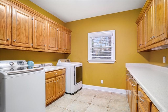 laundry area with baseboards, light tile patterned floors, cabinet space, independent washer and dryer, and a sink