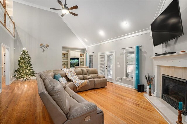 living room with light wood-type flooring, high vaulted ceiling, ceiling fan, and crown molding