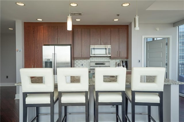 kitchen featuring tasteful backsplash, stainless steel appliances, a center island, hanging light fixtures, and visible vents