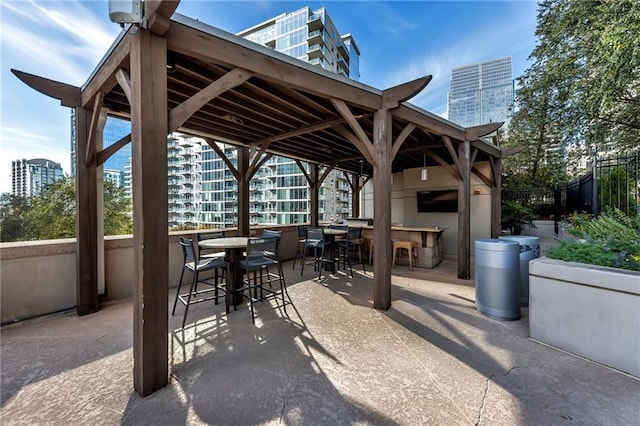 view of patio / terrace with outdoor dry bar, a view of city, and fence