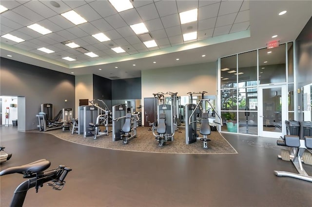 workout area with a wall of windows, a drop ceiling, a towering ceiling, and recessed lighting