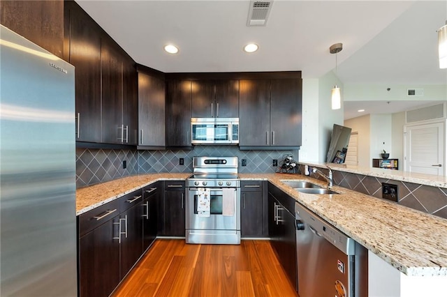 kitchen featuring dark wood-style floors, visible vents, light stone countertops, a sink, and stainless steel appliances