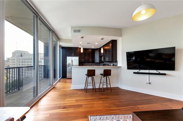 kitchen with visible vents, baseboards, decorative backsplash, light wood-style floors, and stainless steel refrigerator with ice dispenser