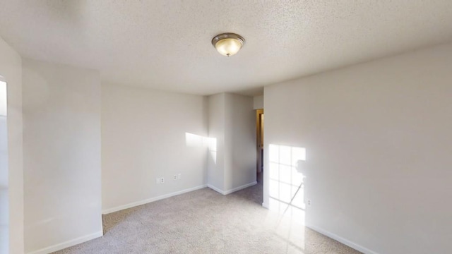 spare room featuring light colored carpet and a textured ceiling