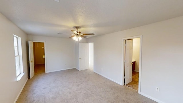 unfurnished bedroom featuring light carpet, a walk in closet, and ceiling fan