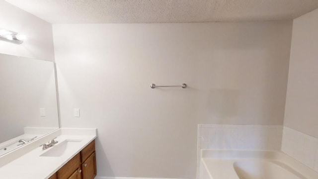 bathroom with vanity, a bathtub, and a textured ceiling