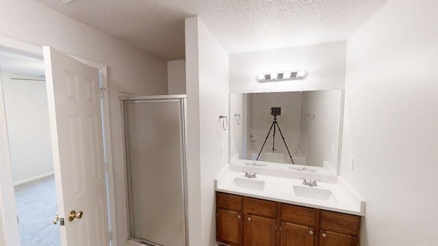 bathroom featuring vanity, a textured ceiling, and a shower with shower door