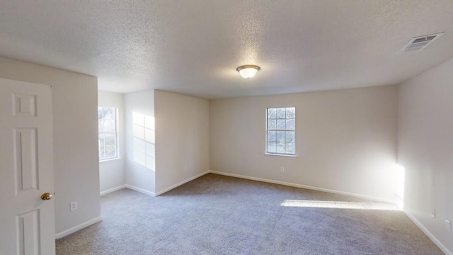 carpeted empty room with a textured ceiling