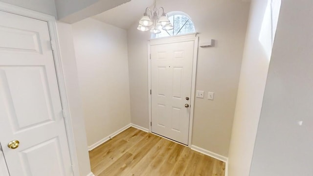 doorway to outside with a chandelier and light hardwood / wood-style floors