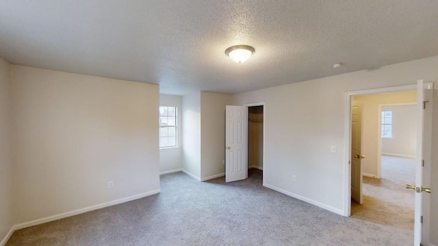 unfurnished bedroom with light carpet, a closet, and a textured ceiling