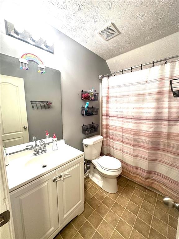 bathroom featuring tile patterned flooring, vanity, a textured ceiling, and toilet