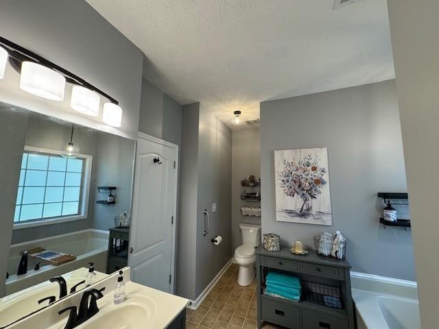 bathroom with a textured ceiling, vanity, toilet, and a bathing tub