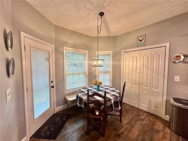 dining room with a chandelier, dark wood-type flooring, and a textured ceiling