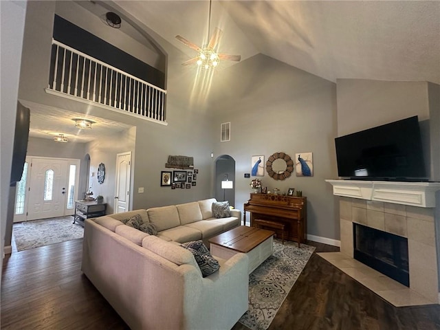 living room featuring hardwood / wood-style flooring, high vaulted ceiling, ceiling fan, and a tiled fireplace