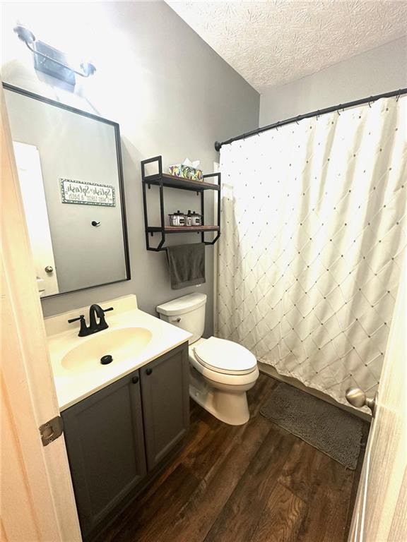 bathroom with hardwood / wood-style floors, vanity, a textured ceiling, and toilet