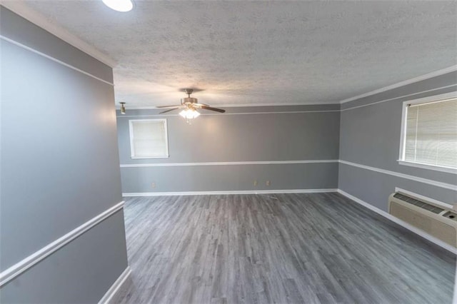 empty room featuring wood-type flooring, a wall mounted air conditioner, a textured ceiling, ceiling fan, and a healthy amount of sunlight