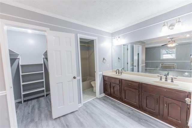 bathroom featuring a wall mounted air conditioner, hardwood / wood-style flooring, vanity, toilet, and a textured ceiling