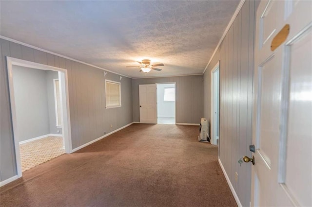 carpeted spare room featuring crown molding, ceiling fan, and a textured ceiling