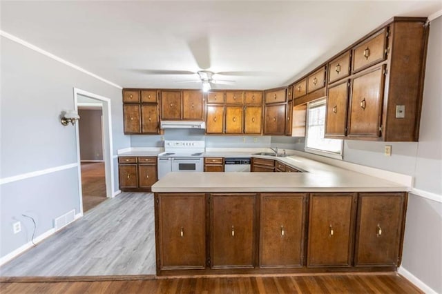 kitchen featuring sink, light wood-type flooring, stainless steel dishwasher, kitchen peninsula, and range with two ovens