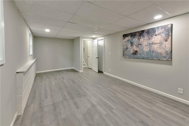 spare room with a drop ceiling and light wood-type flooring