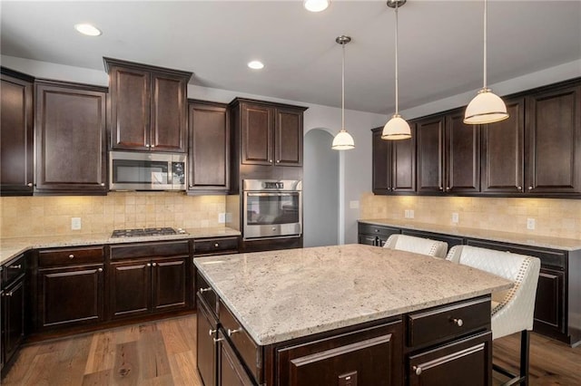1520 Gallant Fox Ln, Suwanee, GA 30024 - kitchen with stainless steel appliances, a kitchen island, dark wood finished floors, light stone counters, and decorative backsplash