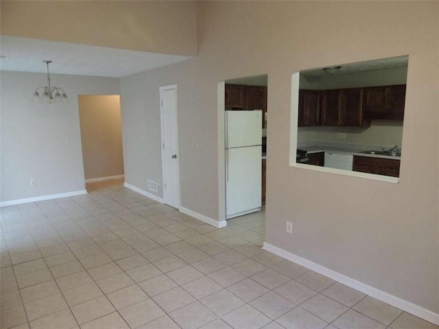 empty room featuring light tile patterned floors, an inviting chandelier, and sink