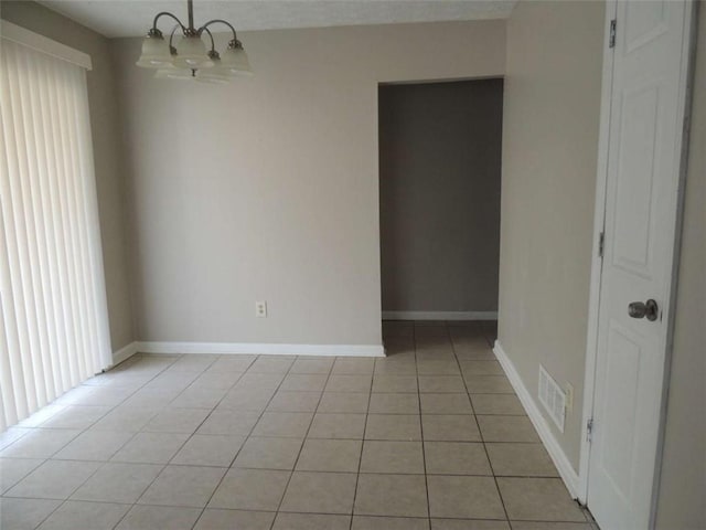 empty room featuring light tile patterned flooring and a chandelier