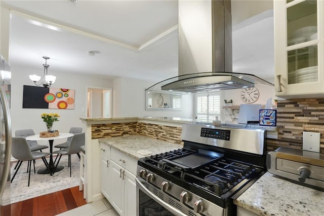 3210 Lake Pointe Cir, Roswell, GA 30075 - kitchen with stainless steel gas stove, island range hood, a chandelier, decorative backsplash, and light stone counters