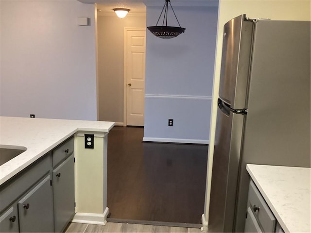 kitchen featuring dark wood-type flooring, crown molding, pendant lighting, and stainless steel refrigerator