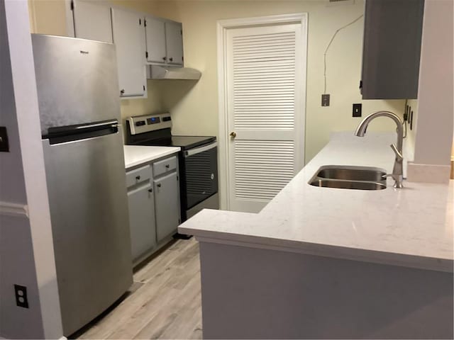 kitchen with gray cabinetry, light hardwood / wood-style floors, appliances with stainless steel finishes, and sink