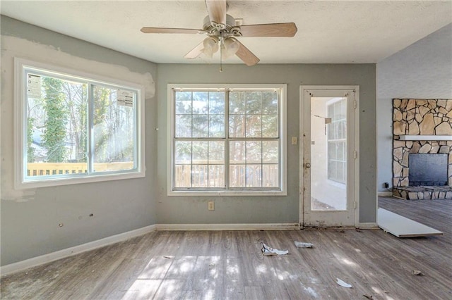 entryway with a ceiling fan, a fireplace, baseboards, and wood finished floors