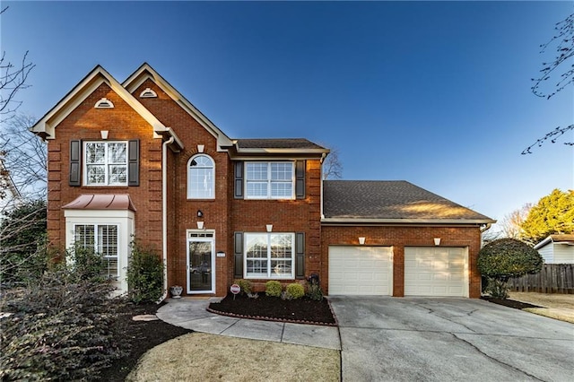 colonial home with concrete driveway, brick siding, an attached garage, and fence