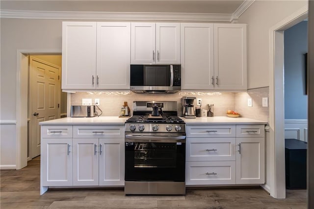 kitchen with stainless steel appliances, light countertops, backsplash, ornamental molding, and white cabinets