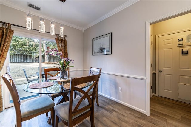 dining area featuring baseboards, wood finished floors, visible vents, and crown molding