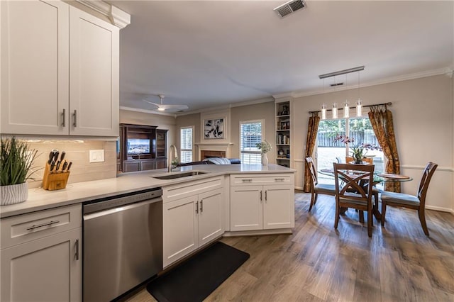 kitchen featuring visible vents, a peninsula, crown molding, stainless steel dishwasher, and a sink