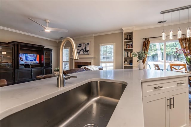 kitchen featuring visible vents, open floor plan, light countertops, a fireplace, and a sink