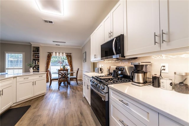 kitchen featuring a wealth of natural light, backsplash, stainless steel gas stove, and visible vents