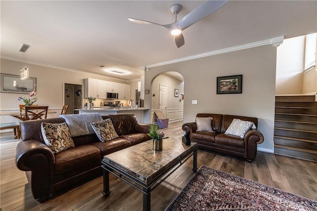 living room featuring arched walkways, crown molding, stairway, and wood finished floors