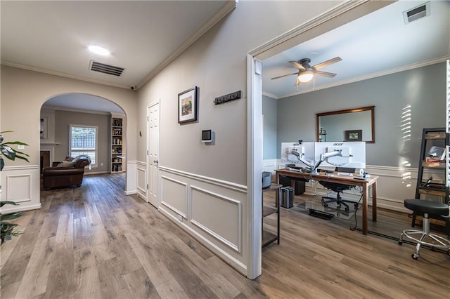 corridor with arched walkways, a wainscoted wall, visible vents, and wood finished floors