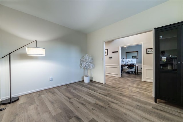 empty room featuring wood finished floors and a decorative wall