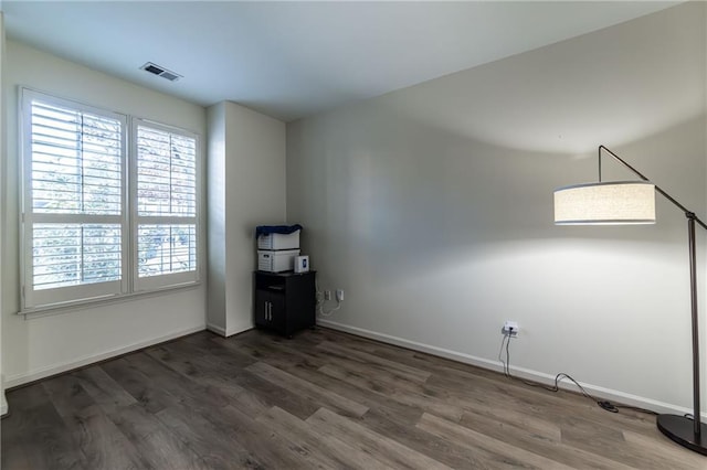 unfurnished room with wood finished floors, visible vents, and baseboards